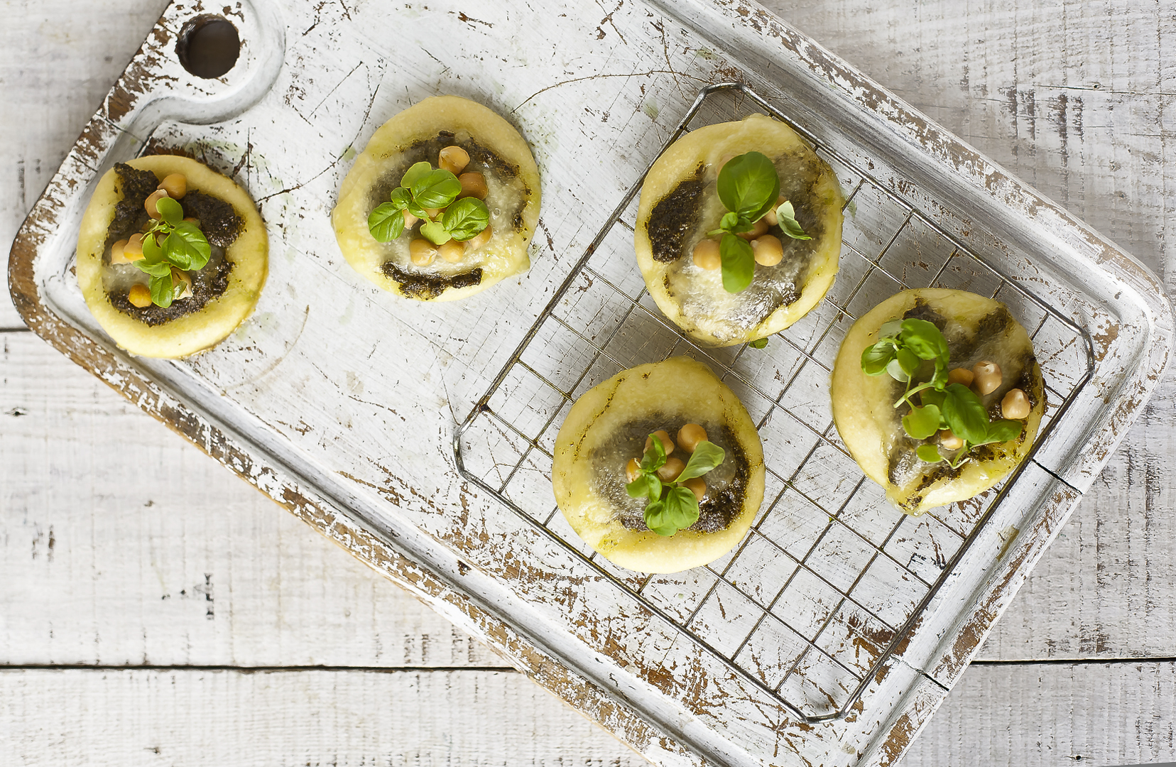 Mini pizze z pesto i orzeszkami piniowymi, gotowe do zapieczenia.