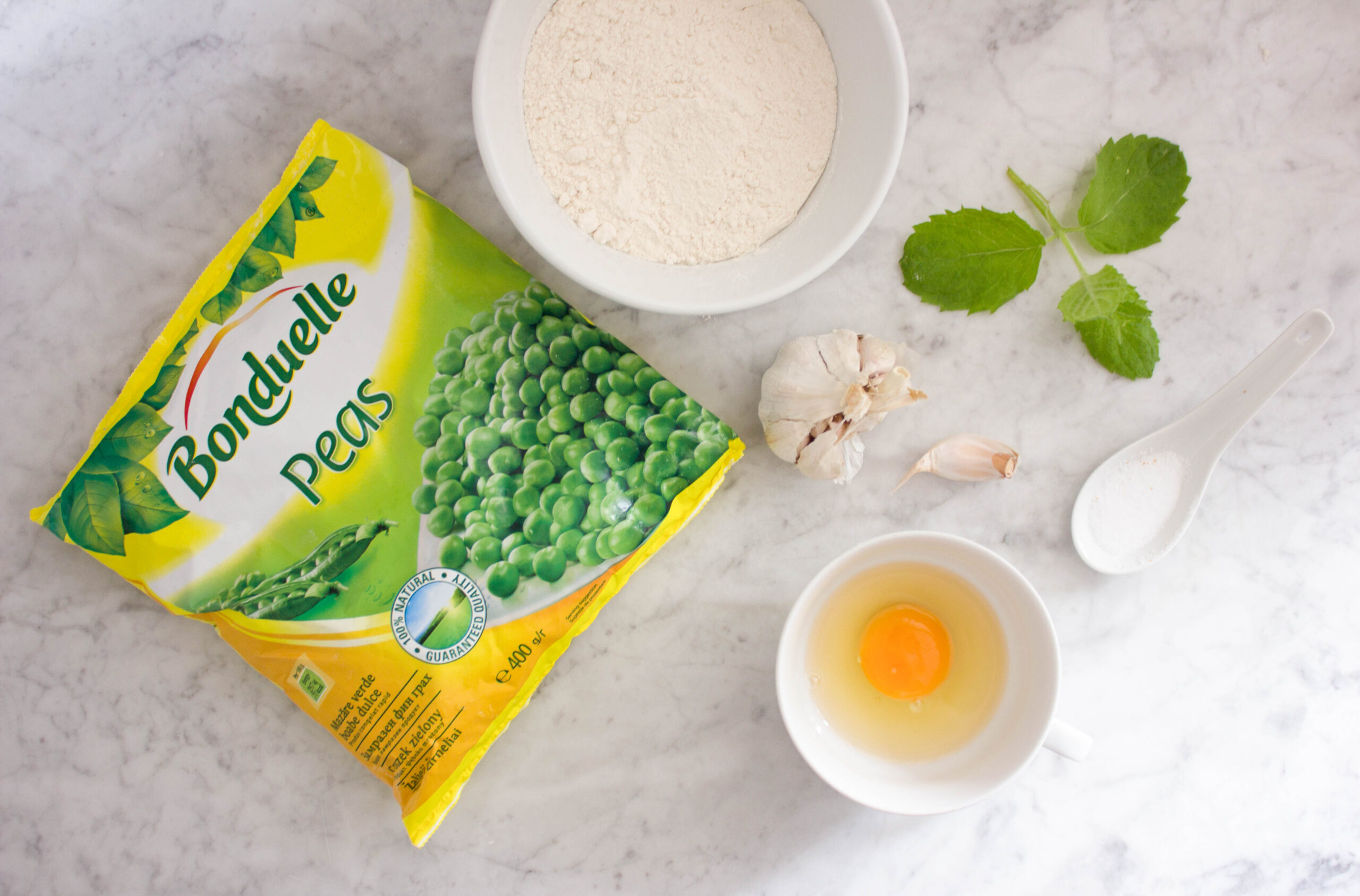 Składniki do przygotowania dania: mrożony groszek, mąka, jajko, czosnek i świeże zioła.