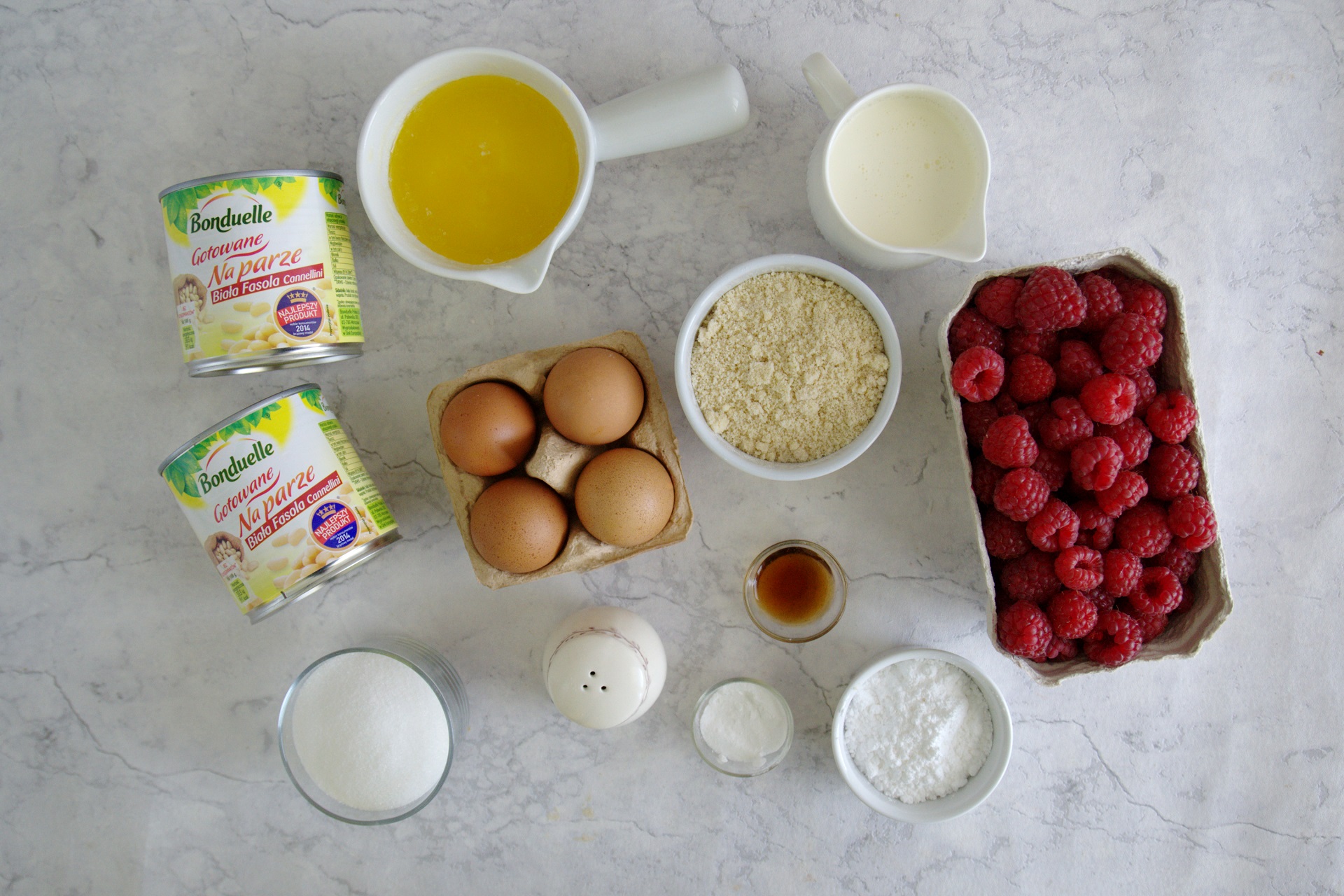 Składniki do przygotowania słodkiego przepisu: świeże maliny, jajka, mąka, cukier, masło i inne niezbędne produkty.