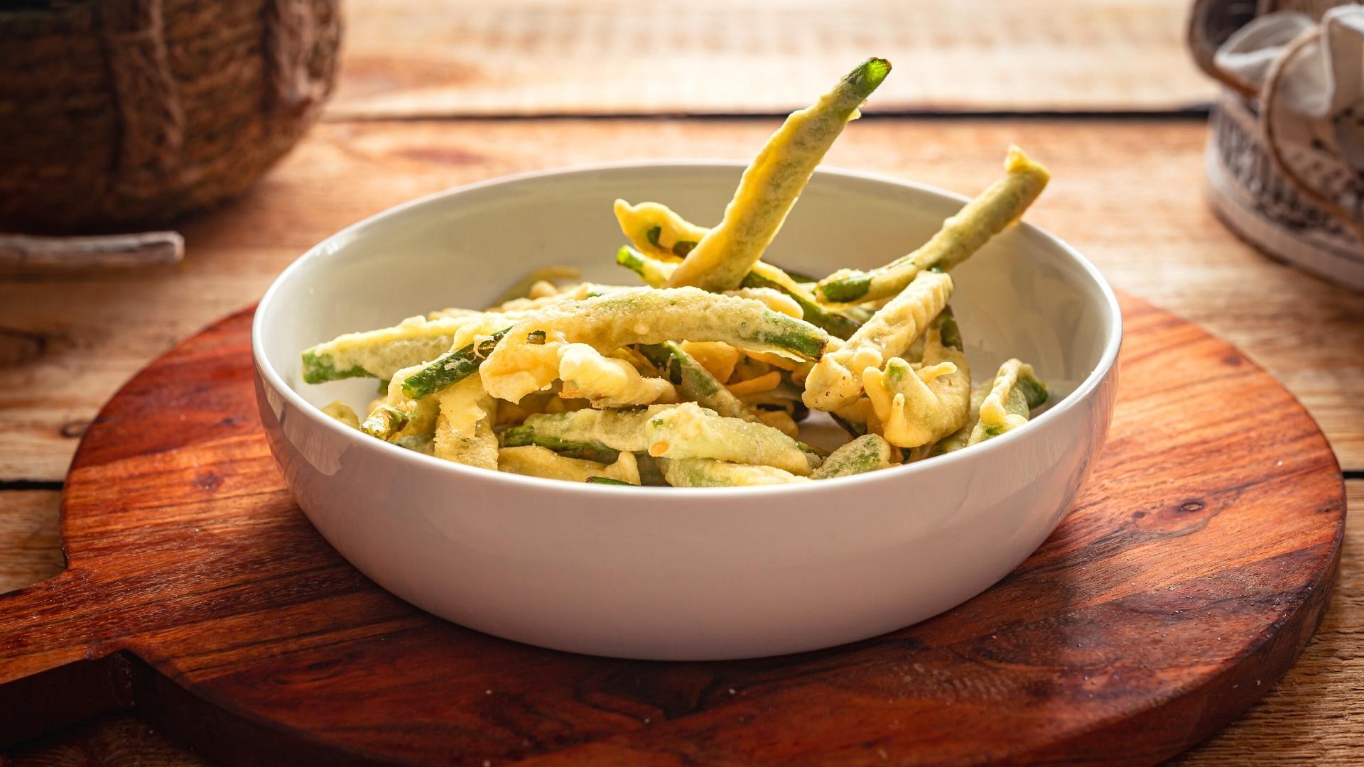 Tempura z zielonych szparagów podana na drewnianej desce.